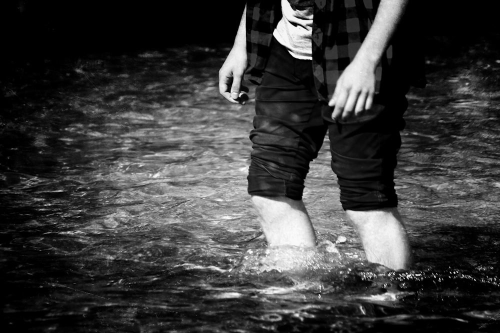 person standing in body of water grayscale photography