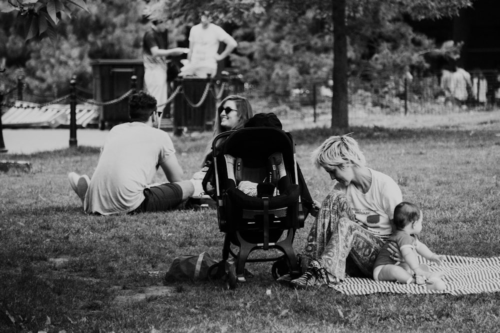 grayscale photography of woman sitting on mat with baby