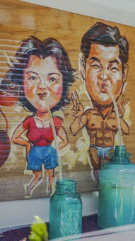 A humorous illustration depicts two cartoonish characters with exaggerated features. The female character wears a red top and blue shorts, while the male character is muscular and wearing a minimal swimsuit. Both characters are connected to green glass bottles via long straws.