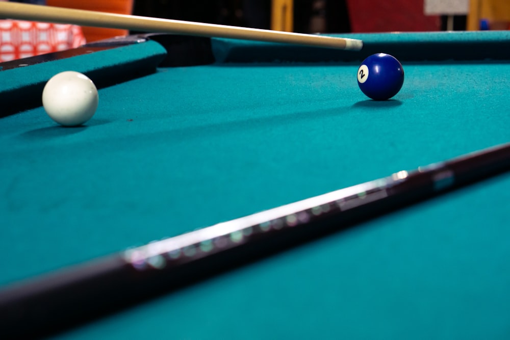 cue ball and 2 ball on pool table near cue sticks