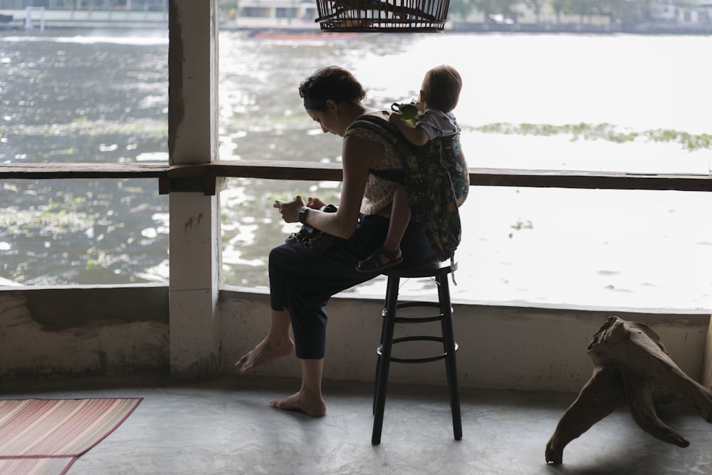 woman carrying baby near body of water