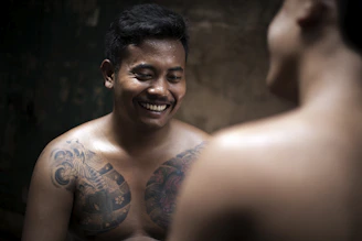 Close-up of a young man showing a healed micropigmentation on his chest with a grateful expression