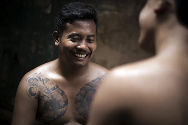 Close-up of a young man showing a healed micropigmentation on his chest with a grateful expression