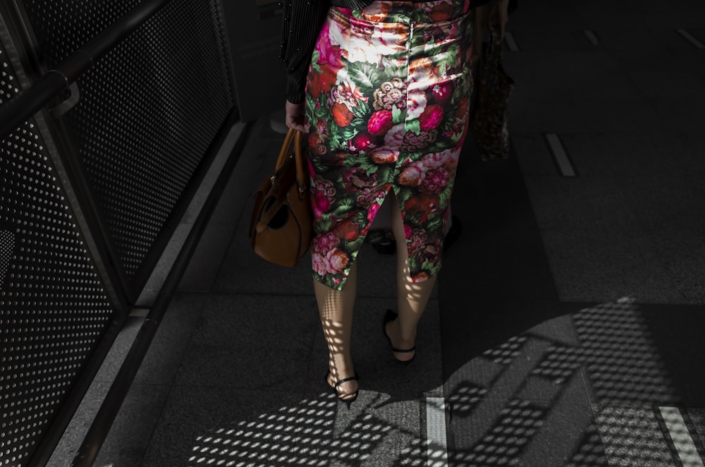 woman wearing multicolored floral dress carrying bag