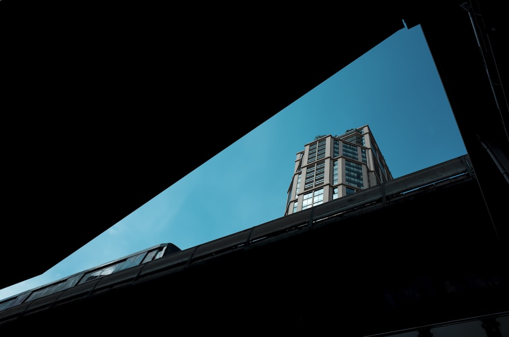 a tall building towering over a city under a blue sky