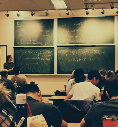 student sitting on chairs in front of chalkboard