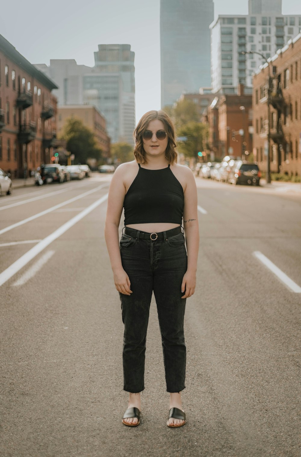 woman standing on concrete road viewing different vehicles parking near buildings