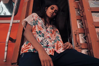 Model wearing a vividtees shirt with a bright, hand-drawn floral design standing against a moody urban wall.