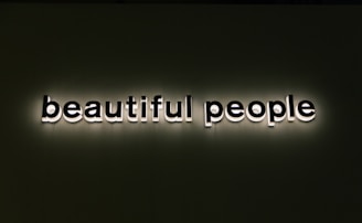 Bold, illuminated text spells out 'beautiful people' against a dark background. The lettering is white with a shadow effect, creating a standout appearance.