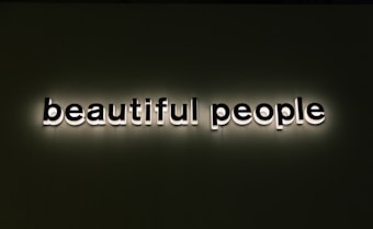 Bold, illuminated text spells out 'beautiful people' against a dark background. The lettering is white with a shadow effect, creating a standout appearance.