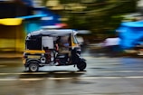 A vibrant auto rickshaw navigating through a bustling city street.
