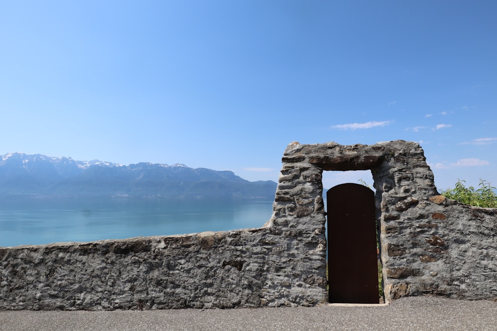 gray stone gate viewing calm sea and mountain under blue and white skies