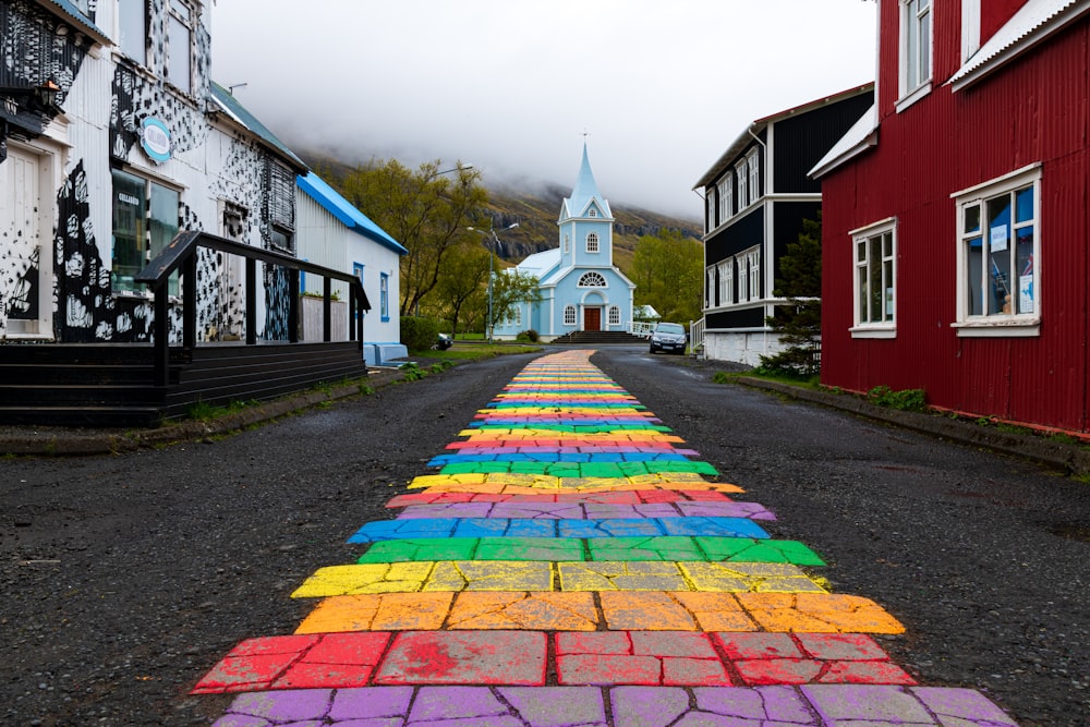 multicolored concrete road in between houses viewing church