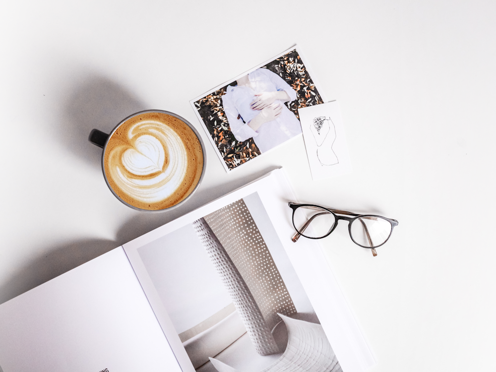 Buch, Tasse Cappuccino, Foto und Brille