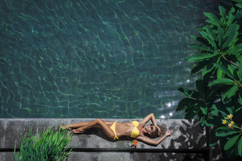 woman lying beside body of water