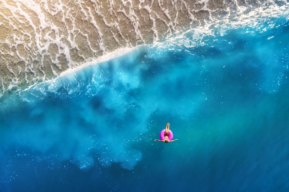 person floating using pink tube