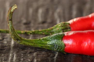 Close-up of vibrant red and green chili peppers sourced from India, highlighting their glossy texture.