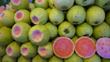 Stacks of sweet potatoes and red guavas ready for wholesale packaging.