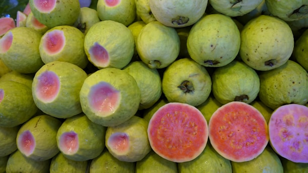 Close-up of vibrant guava sweets arranged on rustic wooden board.