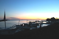 Traditional Basque fishermen boats lined up on the rocky coast at sunset.