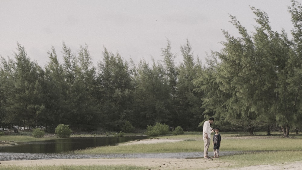 man and boy standing near green trees