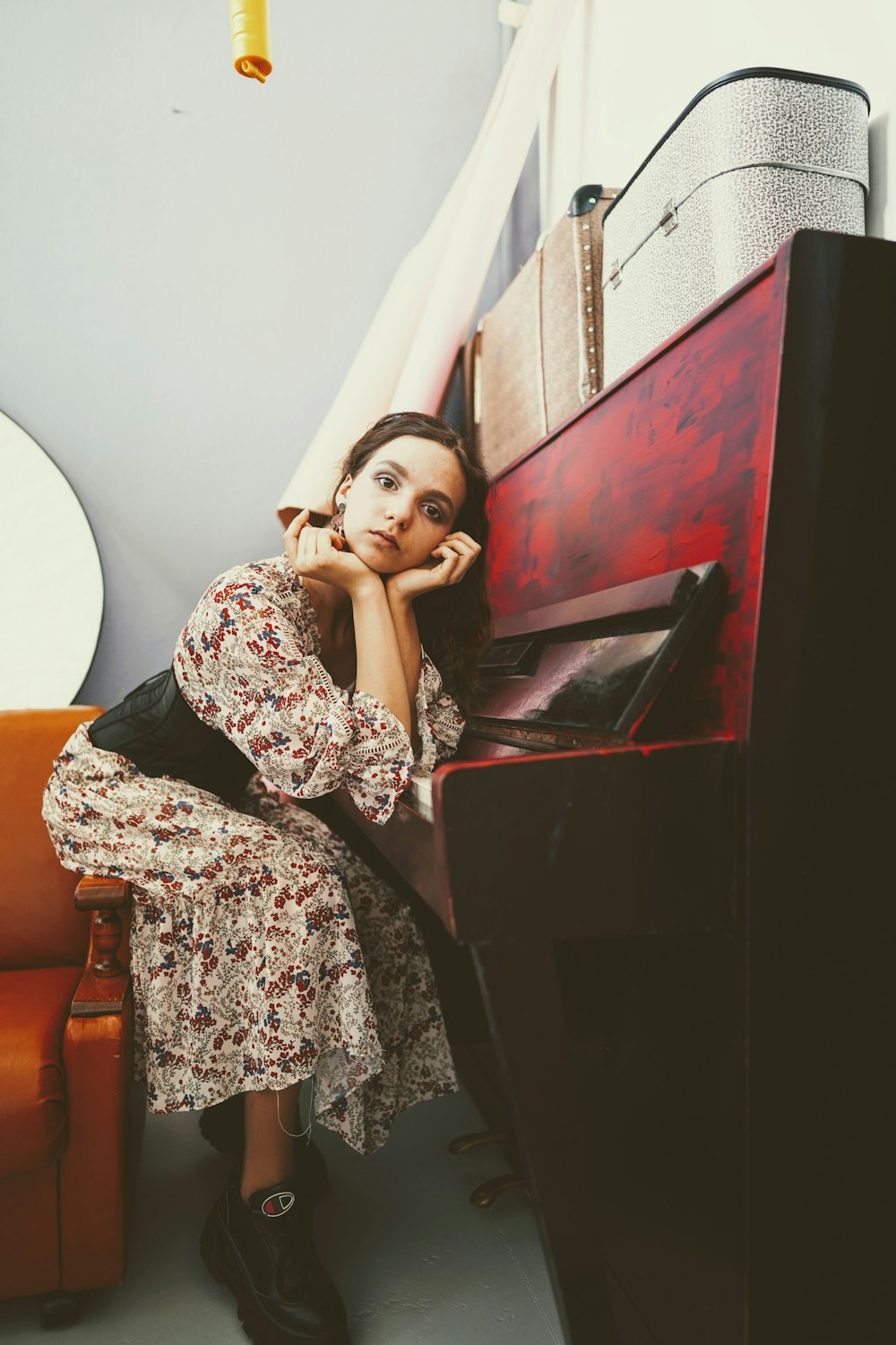 woman leaning on upright piano inside room