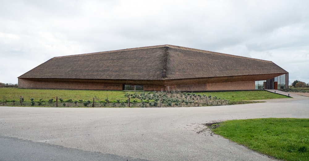 a large building with a grass roof in a field