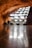 A smooth, reflective floor stretches out towards an abstract structure composed of angled, illuminated panels. The warm, rocky ceiling curves above the scene, suggesting an underground or cave-like environment. The lighting creates a dramatic contrast with the darker surroundings.