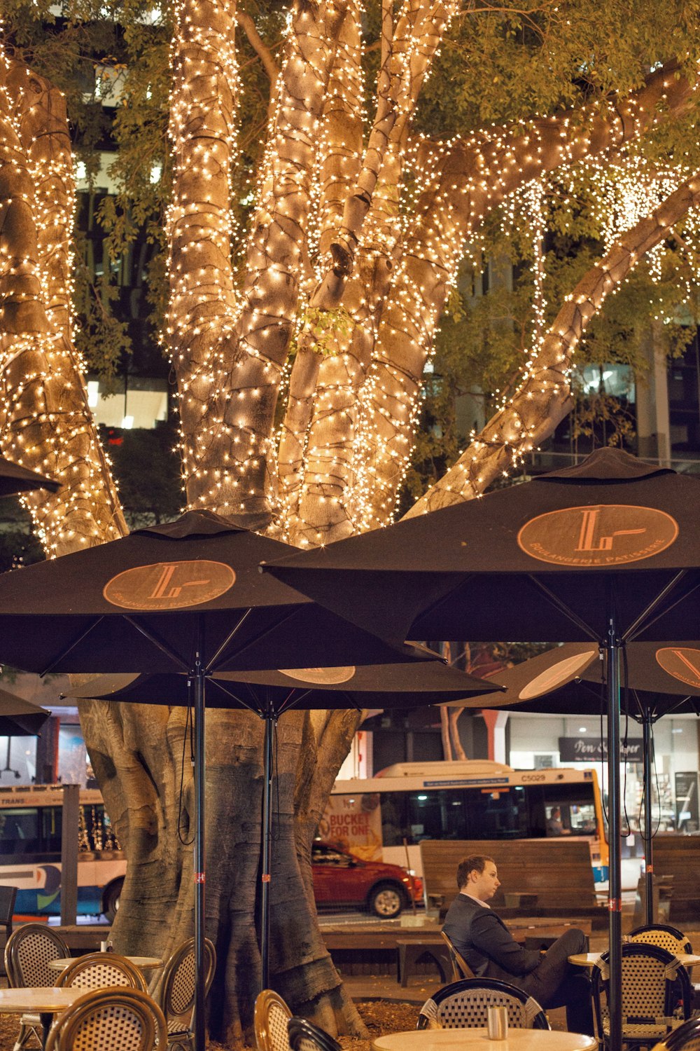 person in gray suit sitting under patio umbrella during night