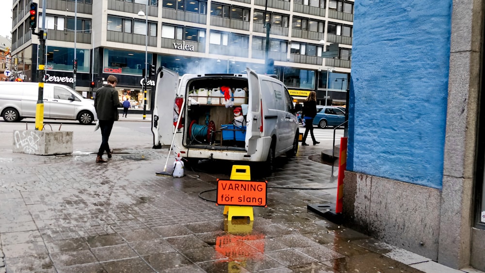 white van showing open door at back near building