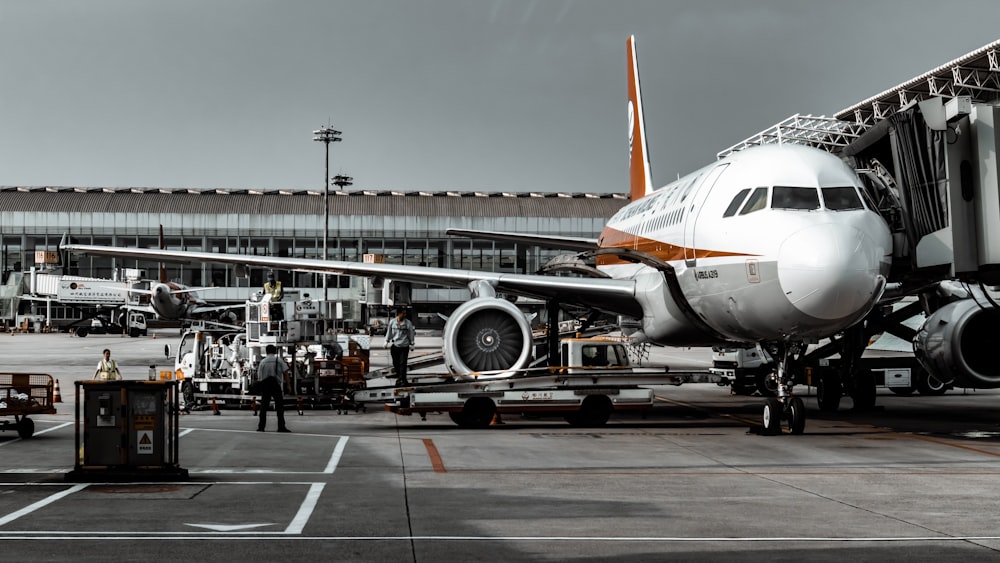 white and orange airplane landing and people going out from airplane