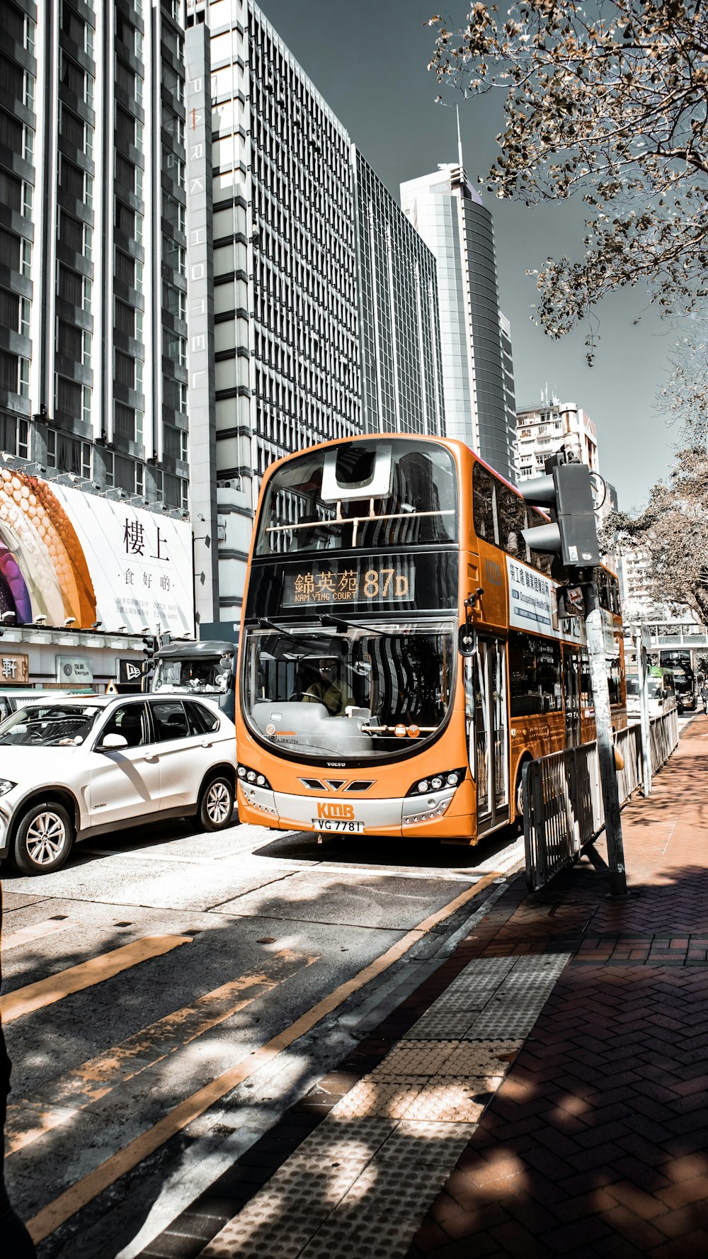 Ônibus laranja de dois andares rodando perto da calçada