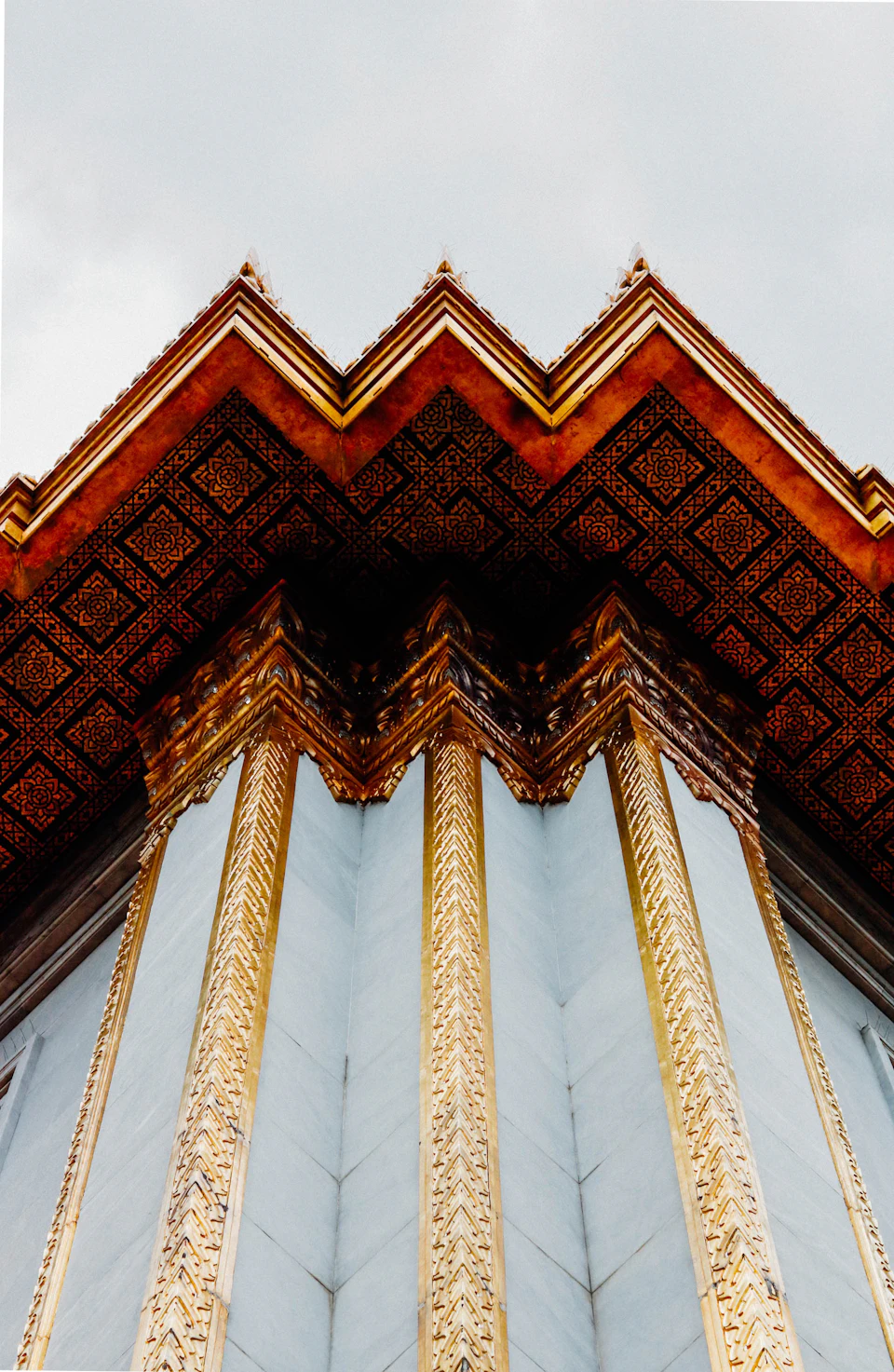The image shows a majestic temple with a striking architectural design featuring four distinct columns, each adorned with intricate gold patterns and designs. The columns are painted in a light blue color that contrasts beautifully with the golden accents on their bases. The perspective of the photo is from below, looking up at the towering structure, emphasizing its grandeur and height.

The sky forms the backdrop for this architectural marvel, adding to the overall visual appeal of the scene.