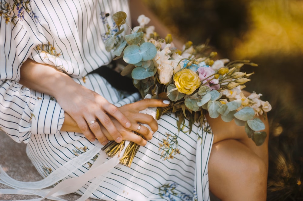 fotografía de enfoque selectivo de mujer sentada sosteniendo ramo de flores