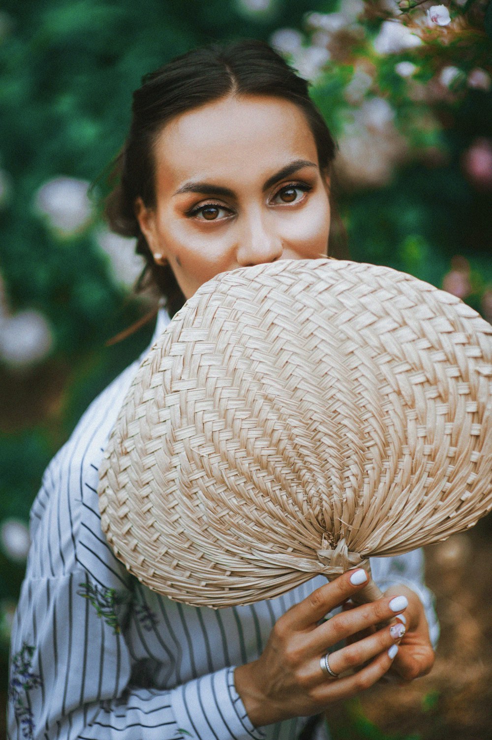 Mujer sosteniendo abanico de mano marrón