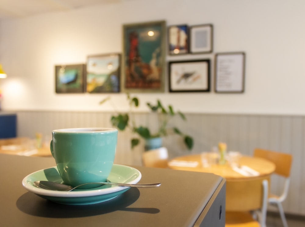 teal ceramic mug on white saucer on table