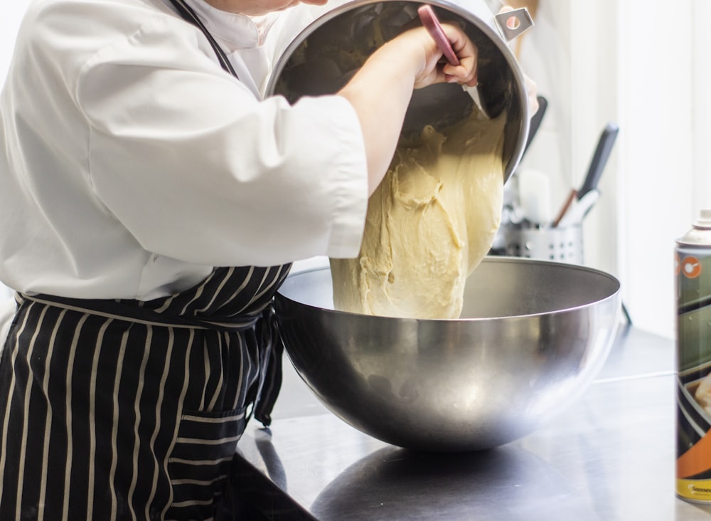 person standing and mixing dough