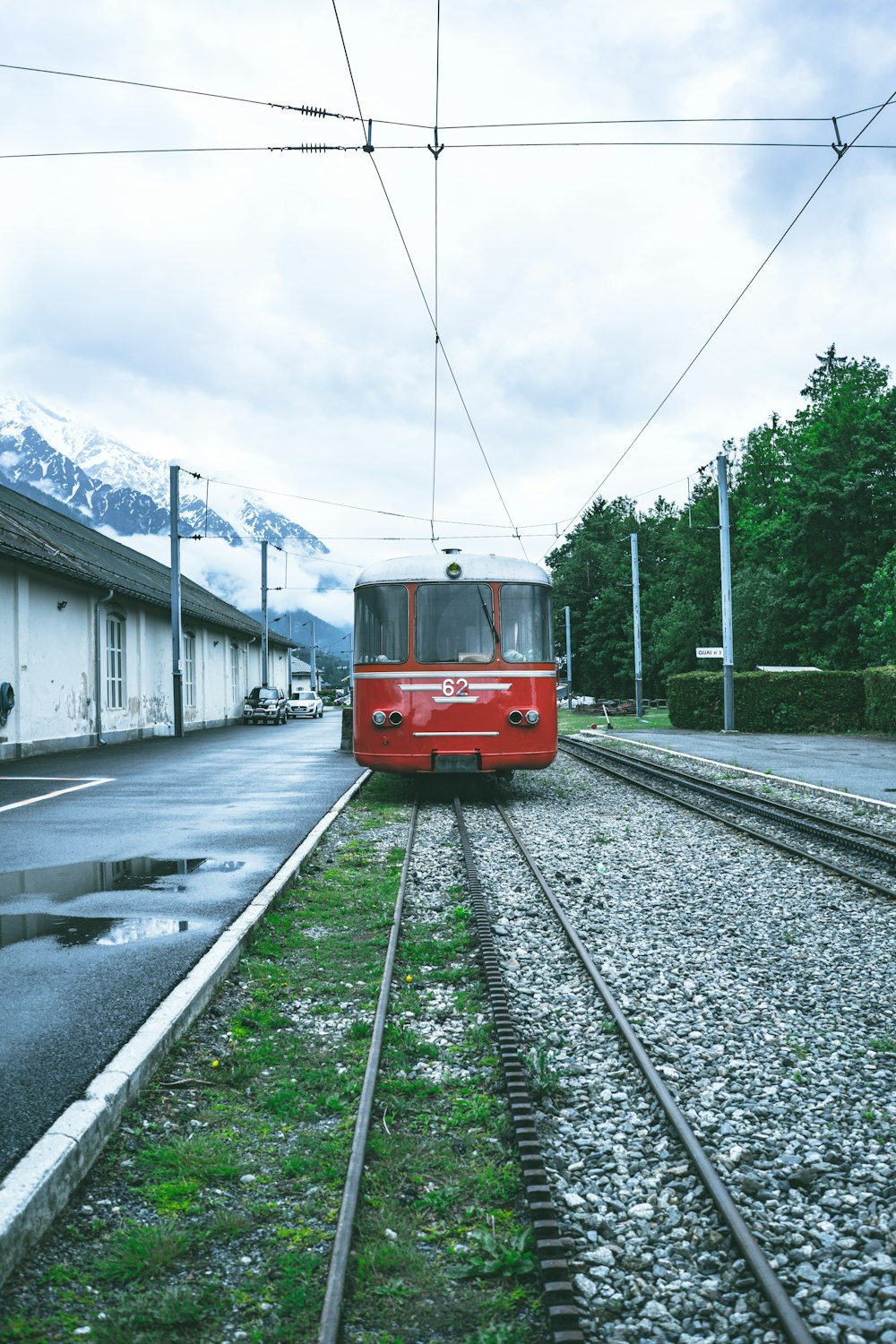 red and white train near buildings and trees under white and blue skies