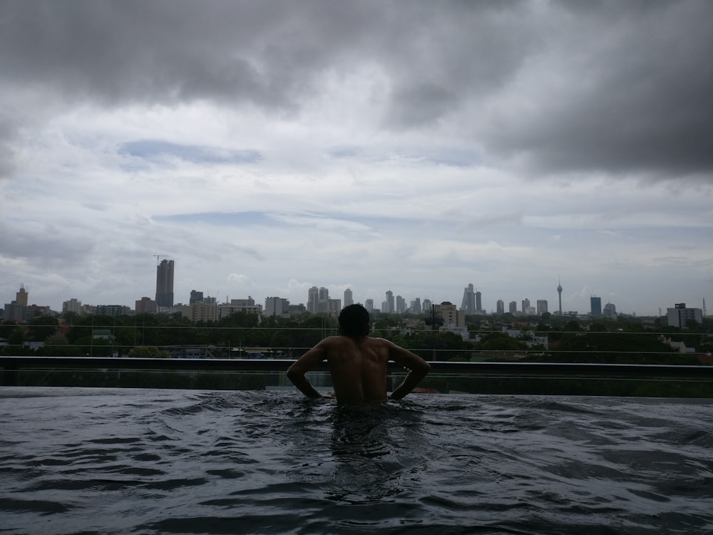 man on swim pool across city building during cloudy daytime