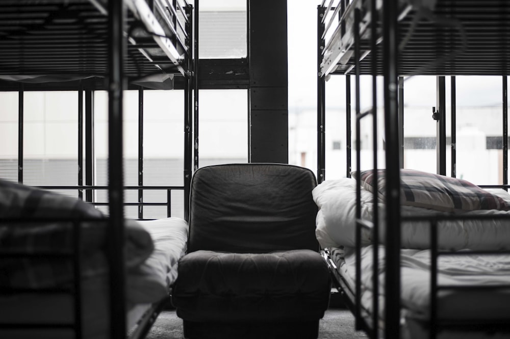 grayscale photo of bunk bed and chair
