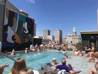 Guests enjoying a sunny rooftop pool with loungers and palm trees around.