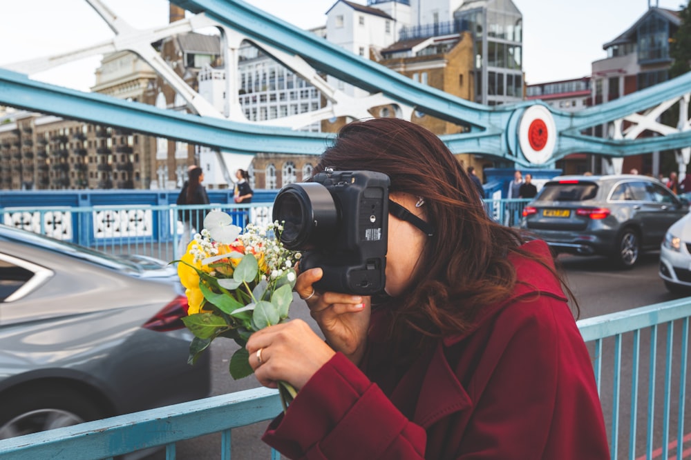 woman holding black DSLR camera