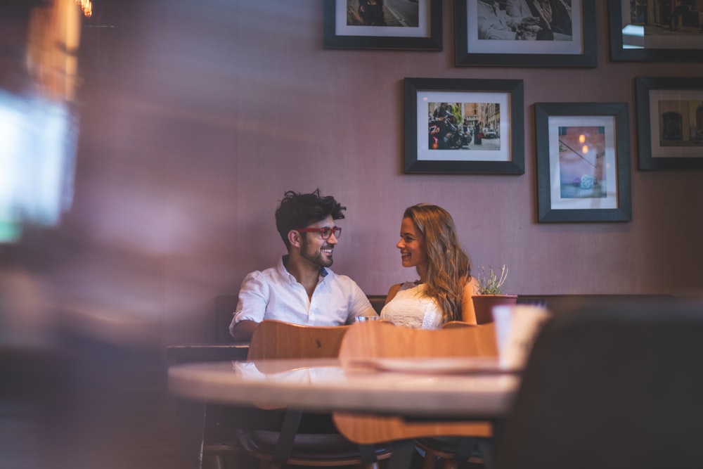 homme portant une chemise blanche regardant une fille assise sur un canapé