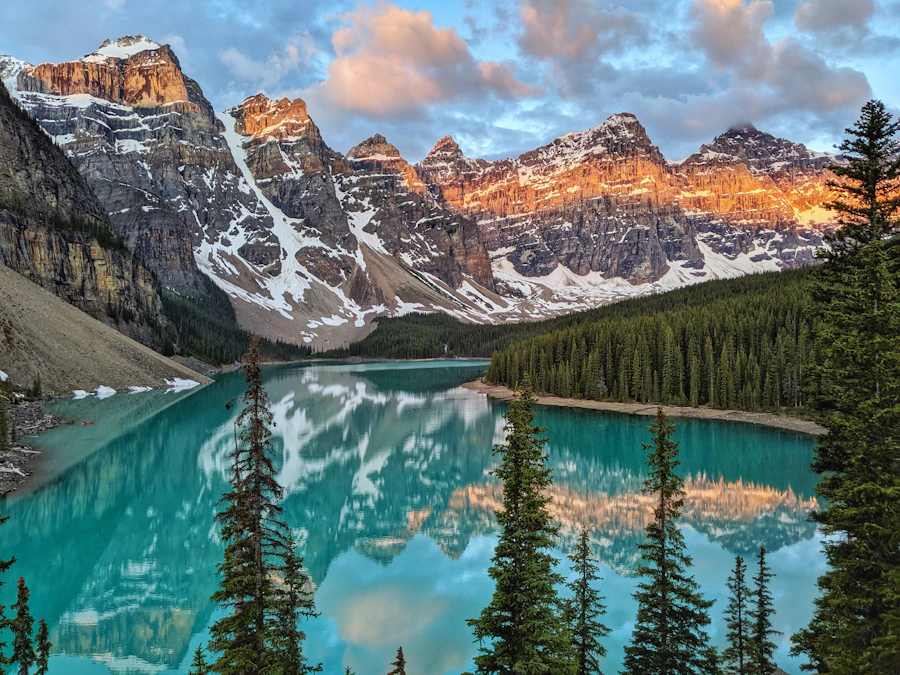 Golden hour light over trees, mountains and water at Moraine Lake area, Banff National Park
