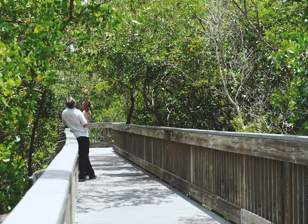 man wearing white shirt standing in bridge during daytime