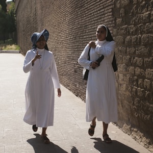 two nun walking near wall