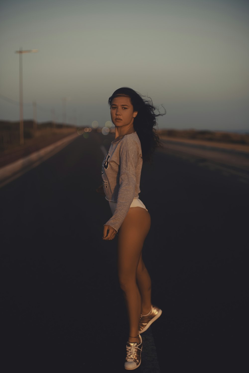 woman in gray sweater standing on road