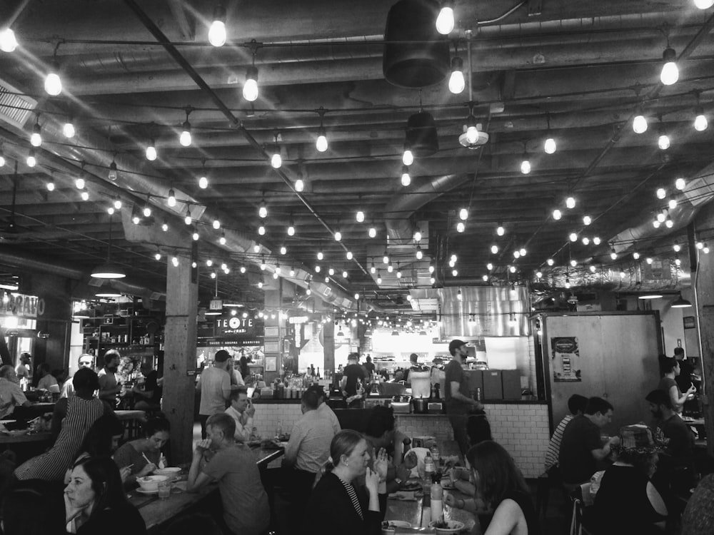 people sitting and others are standing inside bar and restaurant