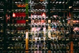 A well-organized wine cellar with multiple rows of wine bottles stored on metal racks. The dim lighting and reflective glass create a cozy and sophisticated ambiance.