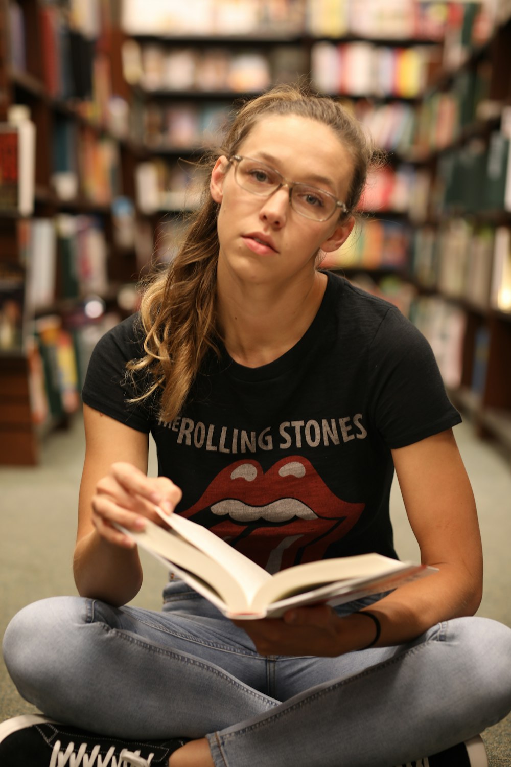 Frau sitzt und liest Buch in der Bibliothek